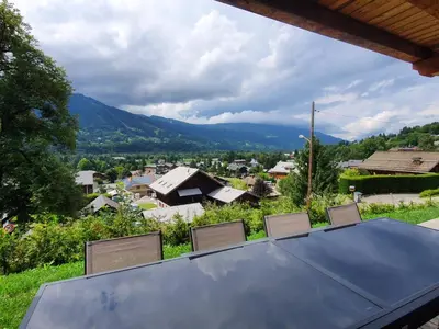 a table with chairs and a view of a town at Plein Soleil 3 bedroom apartment with stunning mountain views in Samoëns