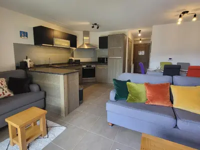 a living room with two couches and a kitchen at Plein Soleil 3 bedroom apartment with stunning mountain views in Samoëns