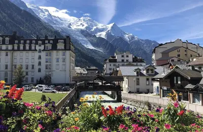 a city with mountains in the background with flowers at Le Petit Paradis - Indoor pool and sauna in Chamonix-Mont-Blanc