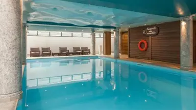 a large swimming pool in a building with a pool at Le Petit Paradis - Indoor pool and sauna in Chamonix-Mont-Blanc