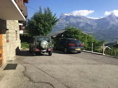 two cars parked on a street with mountains in the background at CHAMBRE INDÉPENDANTE avec SALLE DE BAIN INDÉPENDANTE au RDC d un chalet à 25 kms Chamonix in Saint-Gervais-les-Bains