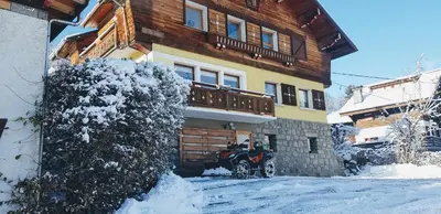 a snowmobile parked in front of a house in the snow at CHAMBRE INDÉPENDANTE avec SALLE DE BAIN INDÉPENDANTE au RDC d un chalet à 25 kms Chamonix in Saint-Gervais-les-Bains