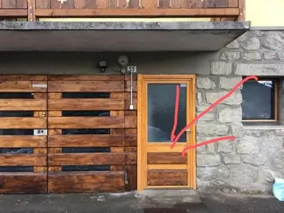 a building with a wooden door and a red ribbon at CHAMBRE INDÉPENDANTE avec SALLE DE BAIN INDÉPENDANTE au RDC d un chalet à 25 kms Chamonix in Saint-Gervais-les-Bains