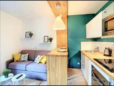 a living room with a blue couch in a kitchen at Centre Saint-Gervais Studio Vert moderne 2 pers proche télécabine in Saint-Gervais-les-Bains
