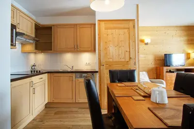 a kitchen with a wooden table and a dining room at Le REFUGE DES PORTES DU MONT BLANC in Vallorcine