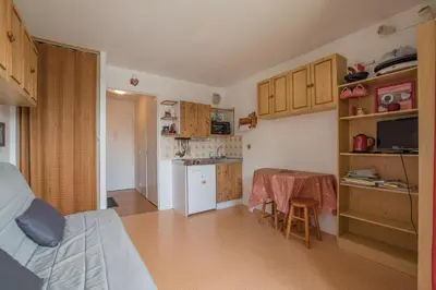 a room with a kitchen with a table and a bed at Studio Ella au cœur du village in Samoëns