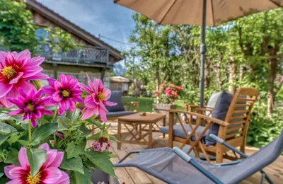 a patio with chairs and an umbrella and flowers at Mazot savoyard situé à 25 kms de CHAMONIX in Saint-Gervais-les-Bains