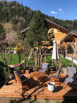 a patio with chairs and a table and an umbrella at Mazot savoyard situé à 25 kms de CHAMONIX in Saint-Gervais-les-Bains