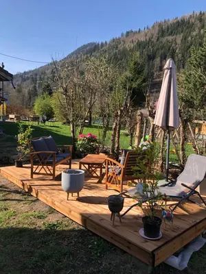 a wooden deck with chairs and an umbrella at Mazot savoyard situé à 25 kms de CHAMONIX in Saint-Gervais-les-Bains