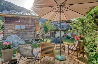 a patio with a table and chairs and an umbrella at Mazot savoyard situé à 25 kms de CHAMONIX in Saint-Gervais-les-Bains