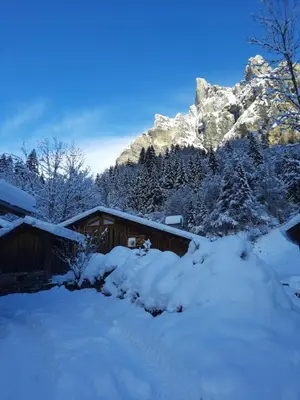 a cabin covered in snow with a mountain in the background at Chalet la corne du chamois in Sixt