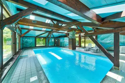 an indoor swimming pool with a ceiling with wooden beams at Prarion ski in ski out and swimming pool ! in Les Houches
