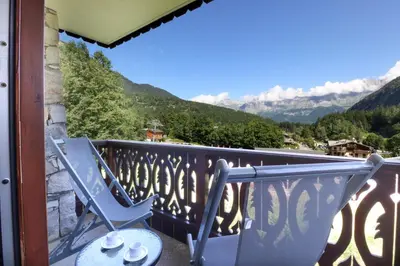 a balcony with two chairs and a table and mountains at Prarion ski in ski out and swimming pool ! in Les Houches
