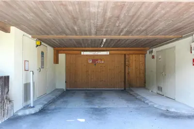 an empty garage with a wooden garage door at Prarion ski in ski out and swimming pool ! in Les Houches