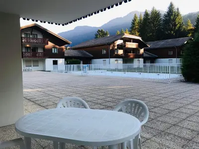 a white table and chairs in a courtyard with buildings at Confortable 3 pièces avec terrasse, idéal pour 6 personnes - FR-1-629-100 in Samoëns