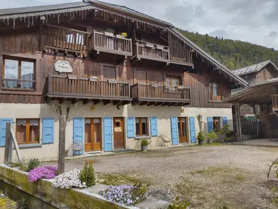 a large building with wooden balconies and blue doors at Chalet La Ferme d'Henriette, à Samoëns in Samoëns