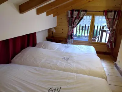two twin beds in a room with a window at Chalet La Ferme d'Henriette, à Samoëns in Samoëns