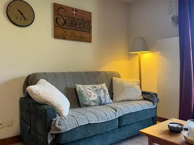 a living room with a blue couch and a clock at Appartement calme à Samoëns avec piscine et WiFi - FR-1-624-101 in Samoëns