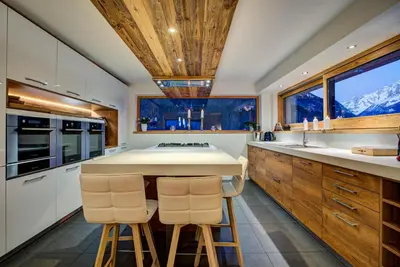 a kitchen with white cabinets and a counter with two bar stools at Chalet Rubicon in Les Houches