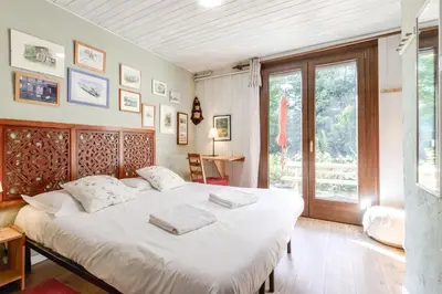 a bedroom with a large bed with white sheets at Clos de l'Ours - 2 chambres - Jardin privé in Chamonix-Mont-Blanc