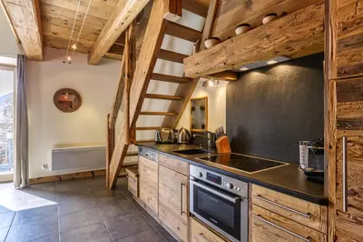 a kitchen with wooden cabinets and a staircase at Appartement Arsene No 6 - Happy Rentals in Le Tour