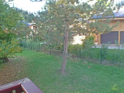 a tree in a yard next to a fence at Confortable 2 pièces cabine à Samoëns avec wifi, parking et animaux admis - FR-1-629-105 in Samoëns