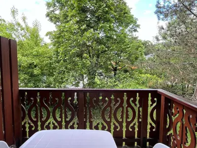 a wooden balcony with a white table and trees at Confortable 2 pièces cabine à Samoëns avec wifi, parking et animaux admis - FR-1-629-105 in Samoëns