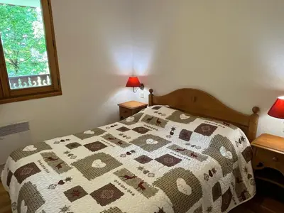 a bedroom with a bed with a quilt on it at Confortable 2 pièces cabine à Samoëns avec wifi, parking et animaux admis - FR-1-629-105 in Samoëns
