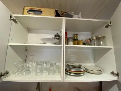 a white cabinet filled with dishes and glasses at Appartement cosy au pied du MtBlanc in Chamonix-Mont-Blanc