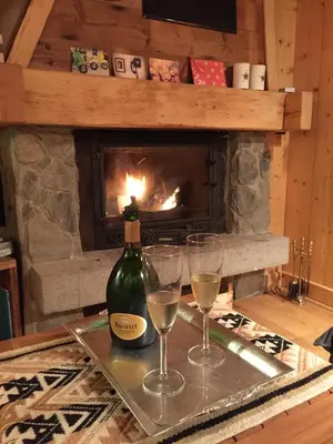 two glasses and a bottle of wine on a table with a fireplace at Appartement cosy au pied du MtBlanc in Chamonix-Mont-Blanc