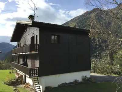 a black and white house with a mountain in the background at Appartement cosy au pied du MtBlanc in Chamonix-Mont-Blanc