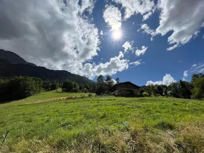 a grassy field with a house in the middle of a field at CHALET TOUDBIOLE haut de chalet in Les Houches