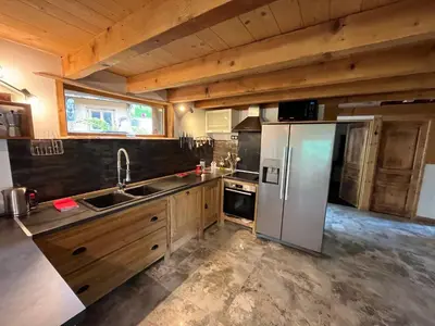 a kitchen with a stainless steel refrigerator and wooden cabinets at CHALET TOUDBIOLE haut de chalet in Les Houches