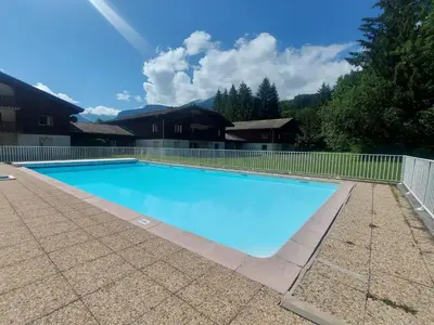 a large blue swimming pool with a fence around it at Appartement familial avec piscines à Samoëns - FR-1-624-103 in Samoëns