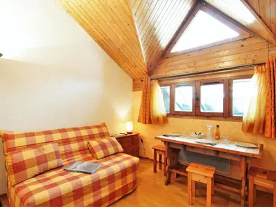 a living room with a couch and a table with a desk at Studio Les Arandellys by Interhome in Les Houches