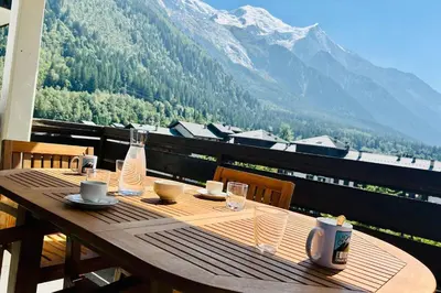 a wooden table on a balcony with a view of a mountain at Apartment Of 55 M With Balcony View Mont Blanc in Chamonix-Mont-Blanc