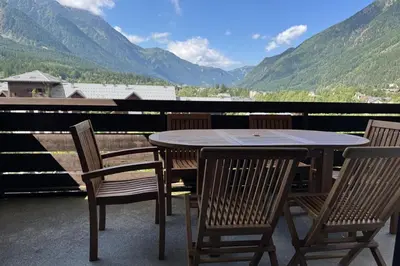 a table and chairs on a balcony with mountains at Apartment Of 55 M With Balcony View Mont Blanc in Chamonix-Mont-Blanc