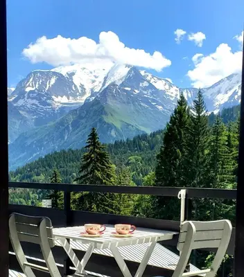a table and chairs on a balcony with a mountain at Appartement Saint Gervais les Bains piscine et vue imprenable Mont Blanc in Saint-Gervais-les-Bains