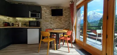 a kitchen with a table and chairs and a window at Appartement Saint Gervais les Bains piscine et vue imprenable Mont Blanc in Saint-Gervais-les-Bains