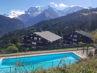 a resort with a swimming pool and mountains in the background at Appartement Saint Gervais les Bains piscine et vue imprenable Mont Blanc in Saint-Gervais-les-Bains