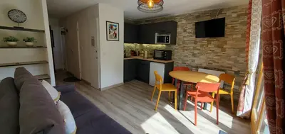 a kitchen and a living room with a table and chairs at Appartement Saint Gervais les Bains piscine et vue imprenable Mont Blanc in Saint-Gervais-les-Bains