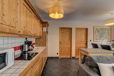 a kitchen with wooden cabinets and a couch in a room at APARTMENT LE PARADIS 2 - ALPES TRAVEL - CENTRAL CHAMONIX (sleeps4-5) in Chamonix-Mont-Blanc