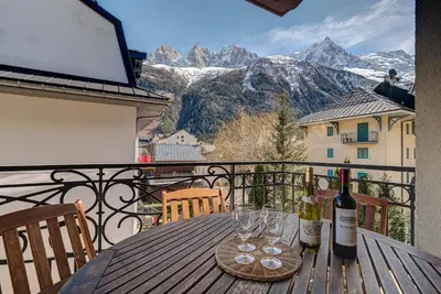 a table with wine glasses on a balcony with mountains at APARTMENT LE PARADIS 2 - ALPES TRAVEL - CENTRAL CHAMONIX (sleeps4-5) in Chamonix-Mont-Blanc