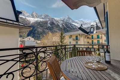 a table with wine glasses on a balcony with mountains at APARTMENT LE PARADIS 2 - ALPES TRAVEL - CENTRAL CHAMONIX (sleeps4-5) in Chamonix-Mont-Blanc