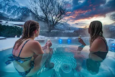 two women in a hot tub with drinks at Tiki Lodge - hot tub & sauna in Chamonix-Mont-Blanc