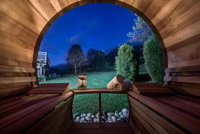 an arched window with a teddy bear sitting on a wooden balcony at Tiki Lodge - hot tub & sauna in Chamonix-Mont-Blanc