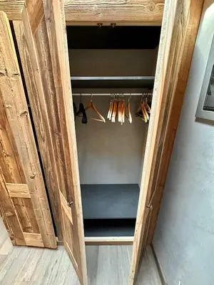 a wooden cabinet with a closet with hangers at chalet Polar in Chamonix-Mont-Blanc