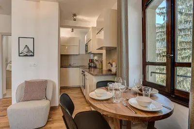 a dining room with a table and chairs and a kitchen at Apartment La Roseraie - Alpes Travel - Central Chamonix (sleeps 2-3) in Chamonix-Mont-Blanc