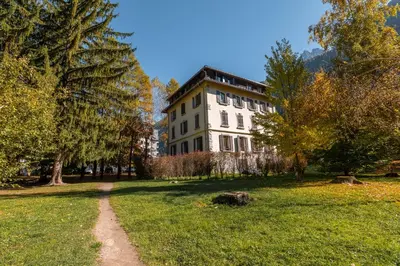 a large white building in a park with a dirt road at Apartment La Roseraie - Alpes Travel - Central Chamonix (sleeps 2-3) in Chamonix-Mont-Blanc