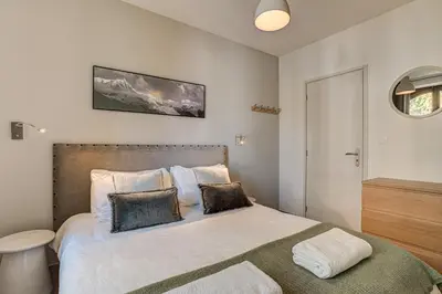 a bedroom with a bed with white sheets and pillows at Apartment La Roseraie - Alpes Travel - Central Chamonix (sleeps 2-3) in Chamonix-Mont-Blanc